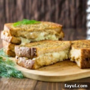 Side view of grilled cheese cut in half with dill on the side.