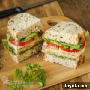 Side shot of a milanese sandwich cut in half on a wooden cutting board with fresh herbs on the side.