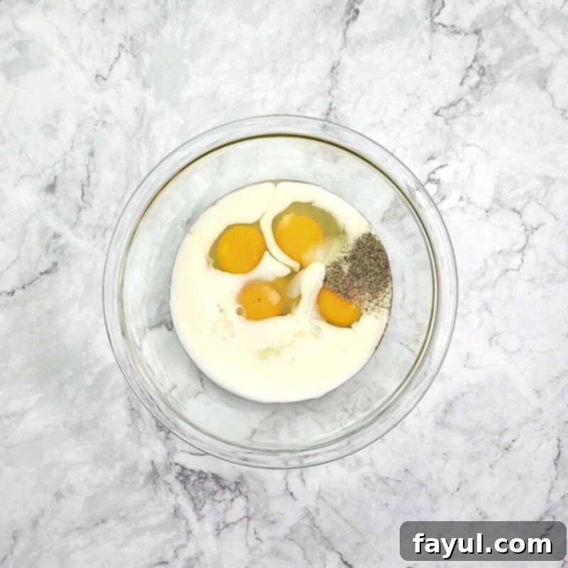Overhead view of process shot 2 - combine the eggs, milk, garlic, salt, and pepper.