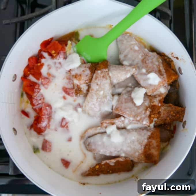 Close up shot of coconut milk poured over all ingredients in white bowl on stove.