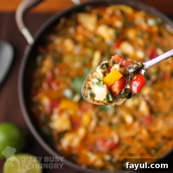 Close up view of stew on a spoon with full pot of stew in the back.