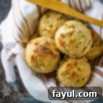 Overhead view of biscuits in a bowl wrapped in a striped towel with a wooden spoon.