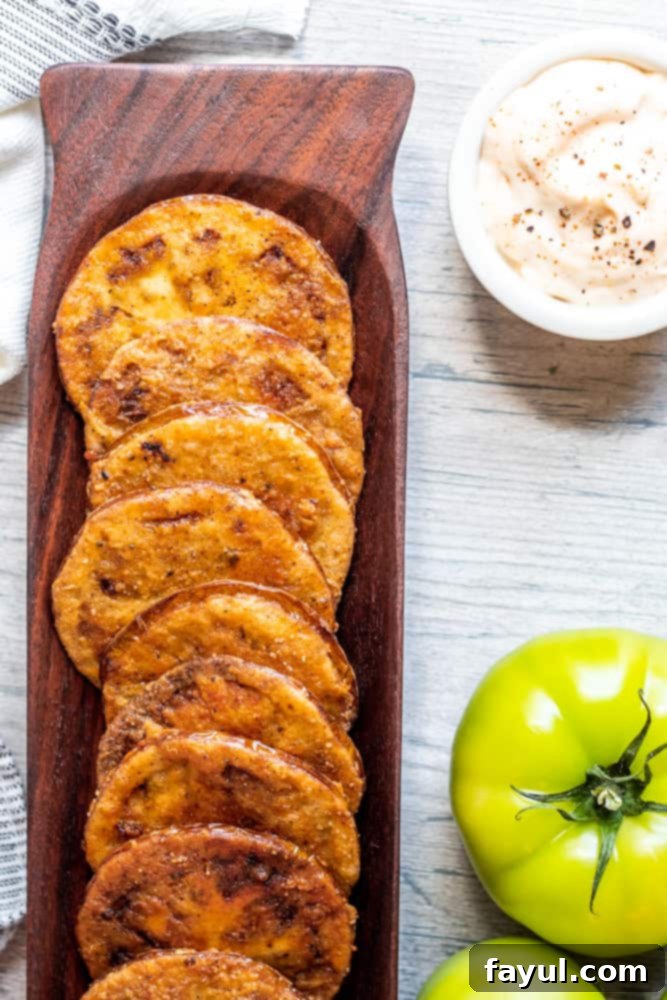 Overhead shot of fried tomatoes in a wooden tray on a white wood counter.