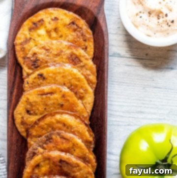 Fried tomatoes in a wood dish on white table.