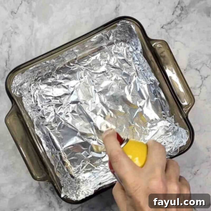 Overhead view of process shot 1 - prepare a 8x8 pan by lining it with aluminum foil and then spraying a light coat of cooking spray on the foil and set aside.