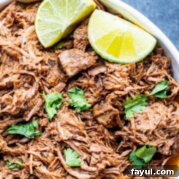 Slow Cooker Mexican Beef Barbacoa 9 Overhead shot of shredded beef in a large white bowl on blue counter.