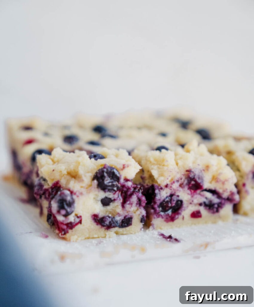 Two hands holding a freshly sliced blueberry pie bar