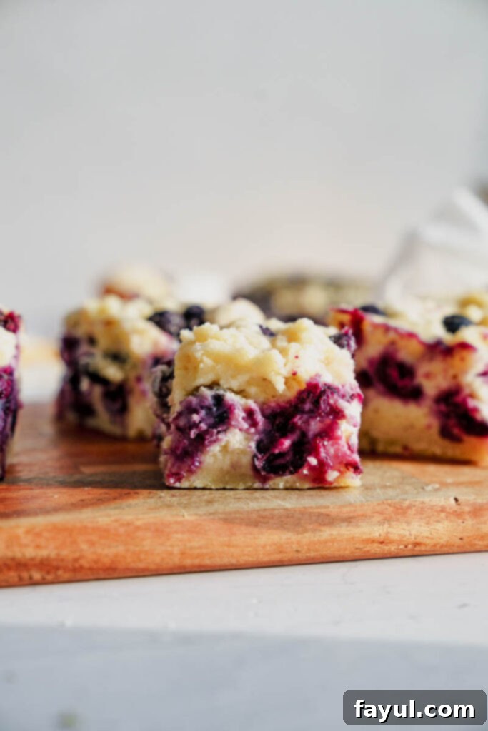 Sliced blueberry pie bars on a white plate with a fork