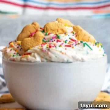 The Ultimate Funfetti Dunker Dip 9 Strait on shot of a creamy Funfetti Cake Dip in a white bowl on a white counter.