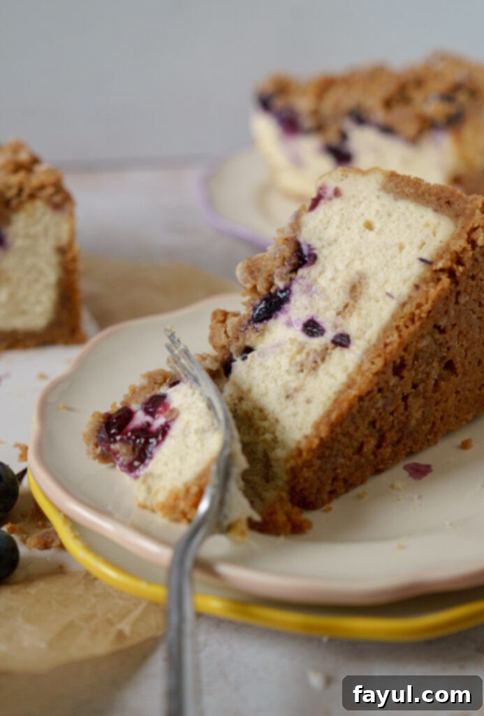 A large, rustic Blueberry Muffin Cheesecake on a wooden board, ready to be sliced.