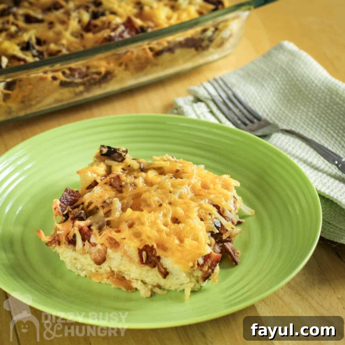 A beautifully plated close-up of a slice of the golden-brown breakfast casserole, garnished with fresh green parsley, with a fork and green linen cloth on the side.