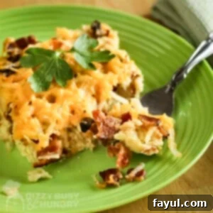 A savory slice of Bacon and Hash Brown Breakfast Casserole on a green plate, with a fork digging in and a green cloth napkin on the side.