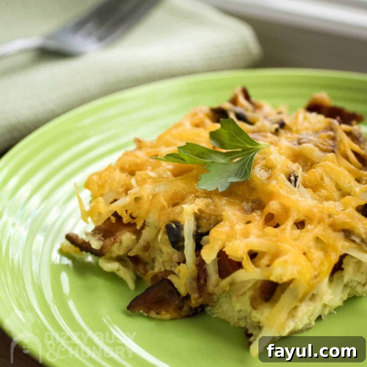 A close-up, tempting shot of a perfectly baked slice of breakfast casserole, generously garnished with fresh parsley, served on a cheerful green plate.
