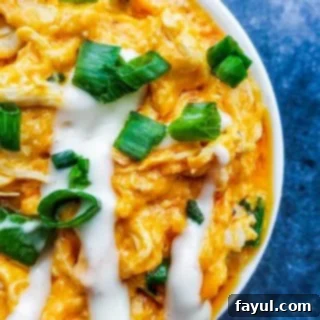 Overhead close up shot of baked buffalo chicken dip in a white bowl, looking deliciously bubbly.