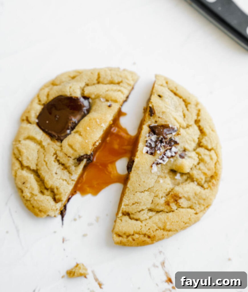 Close-up of a stack of freshly baked salted caramel chocolate chip cookies, showing gooey centers