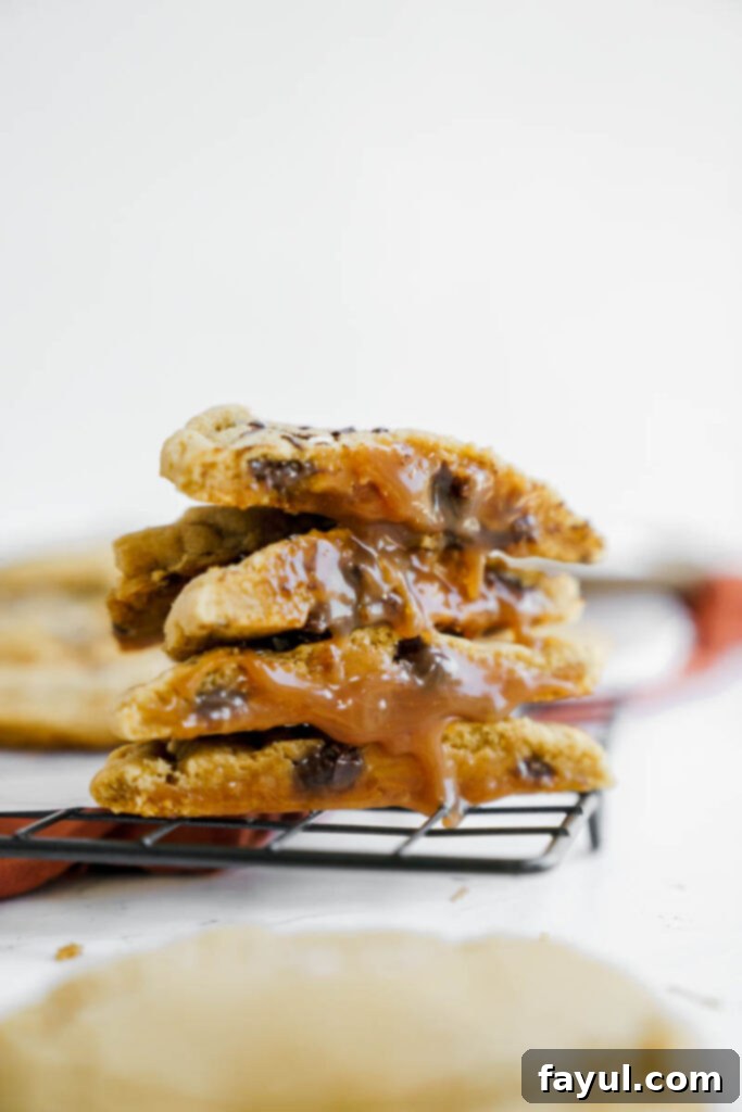 Hand holding a warm, gooey salted caramel chocolate chip cookie, with caramel visible