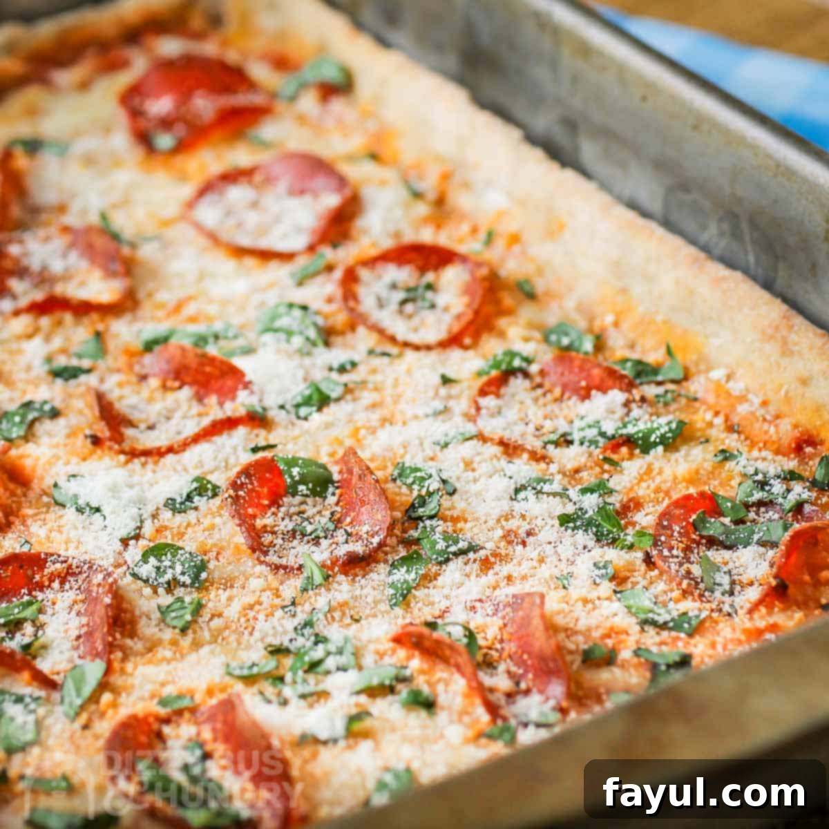 Angled side shot of full pan pizza garnished with parmesan cheese and basil.