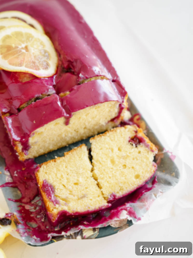Close-up of a slice of Lemon Loaf Cake with Blueberry Glaze, showing the moist crumb and vibrant purple topping