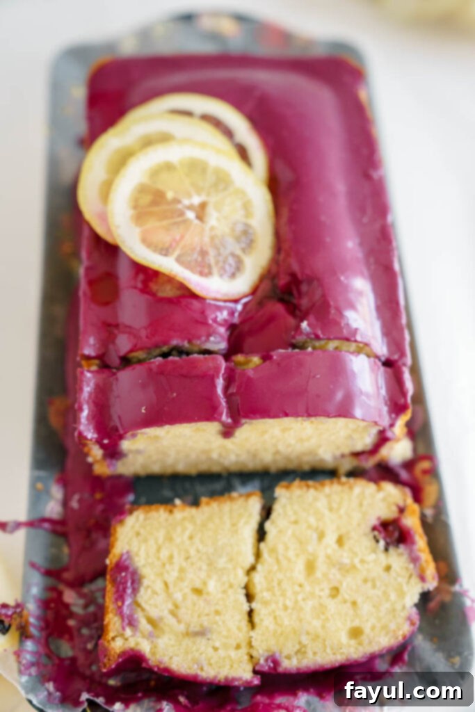 Two slices of lemon loaf cake with blueberry glaze on a white plate, showcasing the thick purple glaze and moist texture.