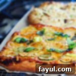 Close-up of a Zucchini Flower Pizza, showing tender zucchini slices and delicate blossoms on a cheesy crust.