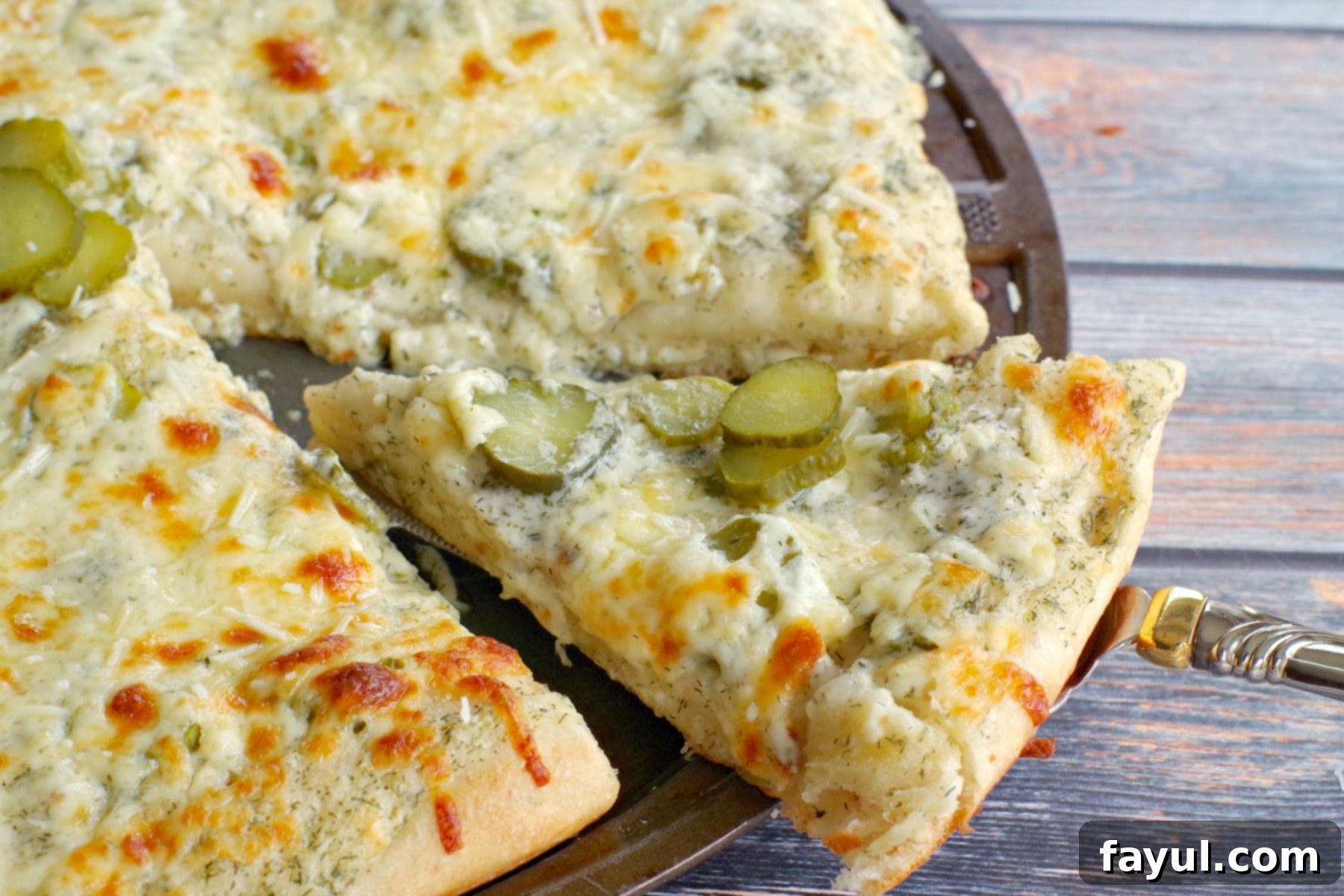 Dill Pickle Pizza, showing slices of pickles and fresh dill on a cheesy, creamy base.