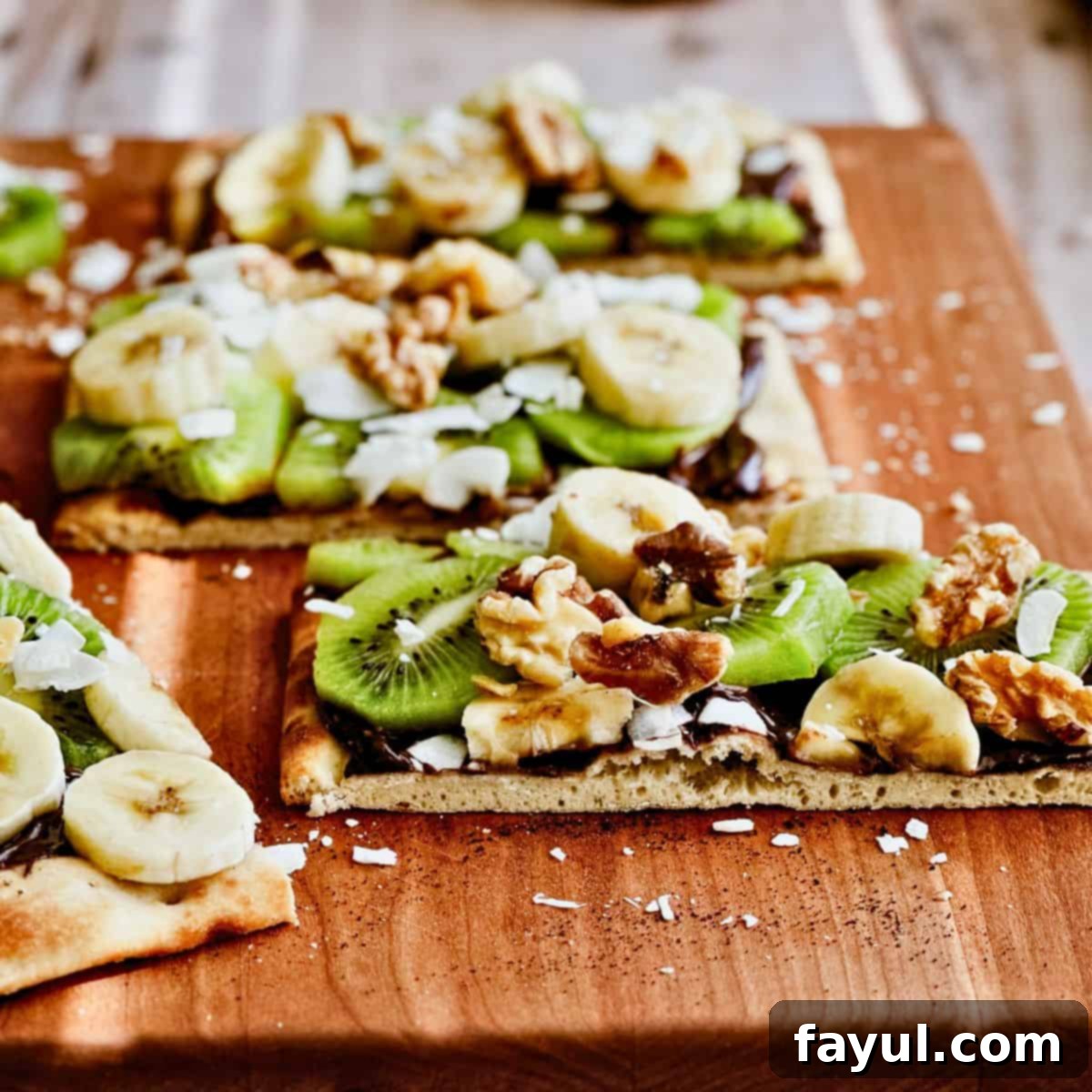 Banana Kiwi Dessert Pizza, featuring a crisp base, rich chocolate spread, and fresh banana and kiwi slices, garnished with toasted coconut and nuts.