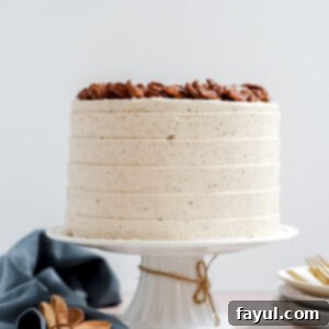 A beautifully decorated whole Maple Pecan Cake with layers visible and topped with candied pecans.