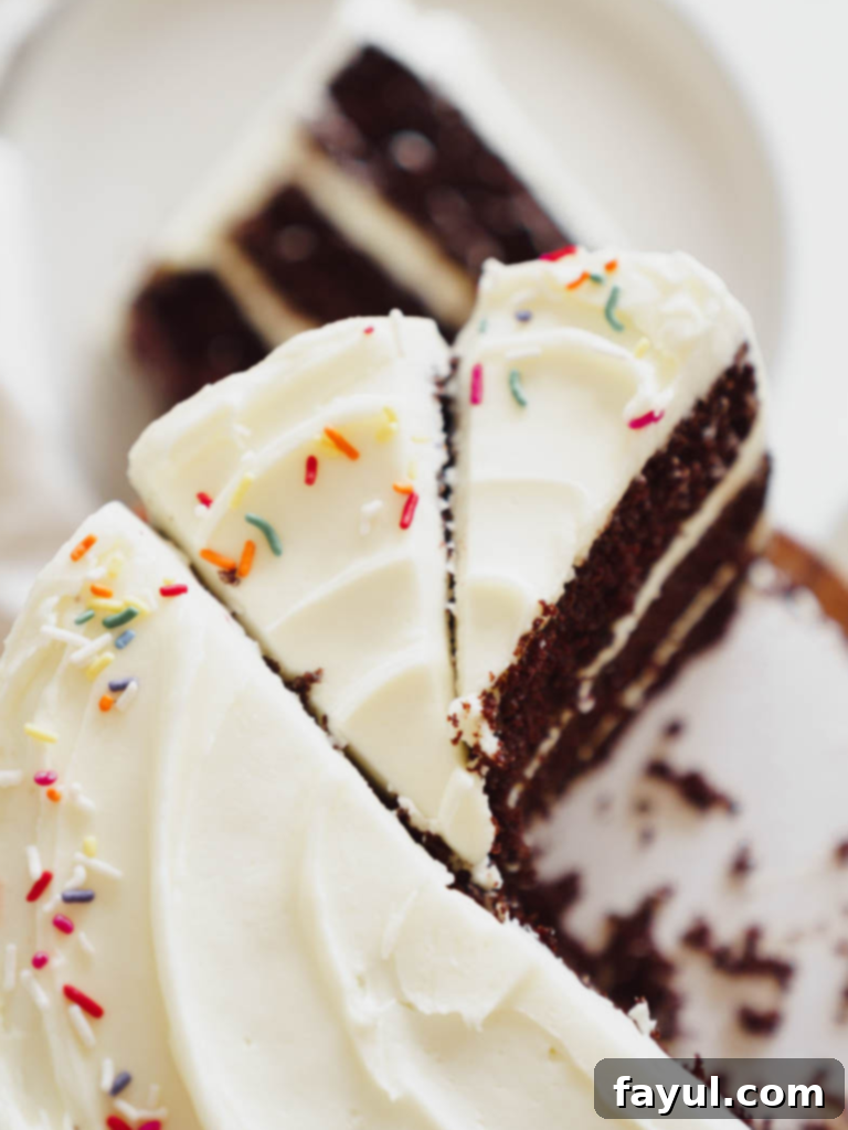 Decadent chocolate cake with creamy white cream cheese frosting on a cake stand, ready to be sliced.