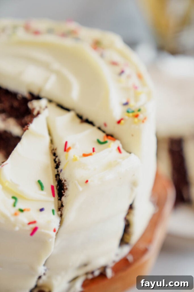 A large slice of rich chocolate cake with cream cheese frosting and sprinkles.