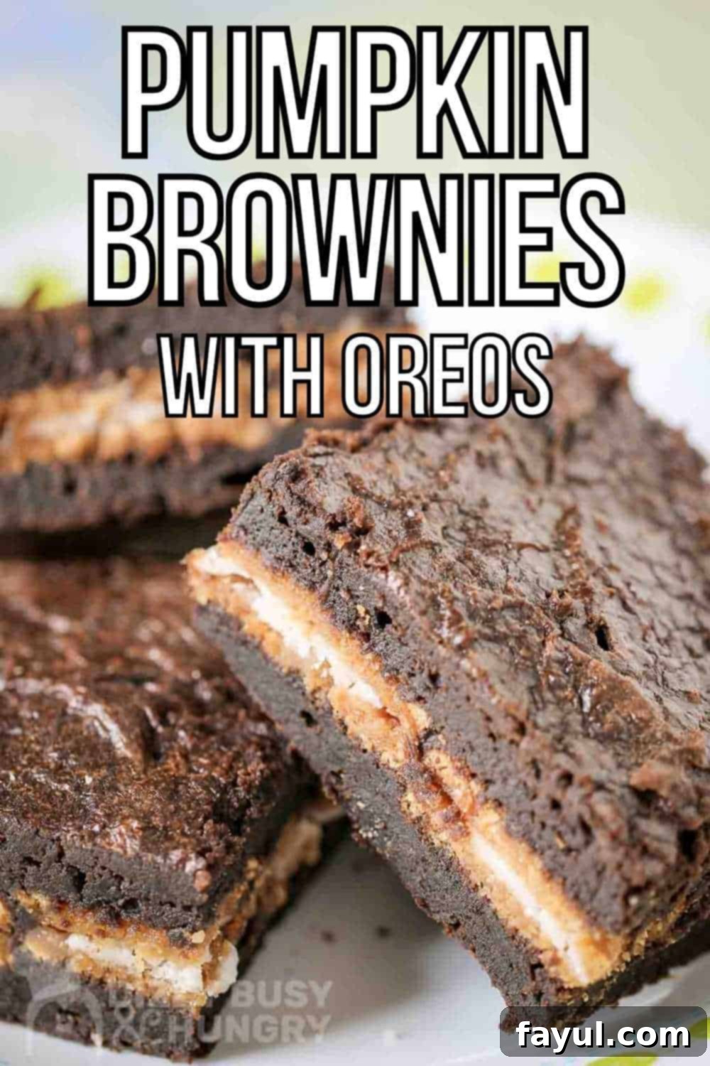 Three fudgy pumpkin Oreo brownies leaning on each other on a white plate, showcasing their moist texture and cookie layer.