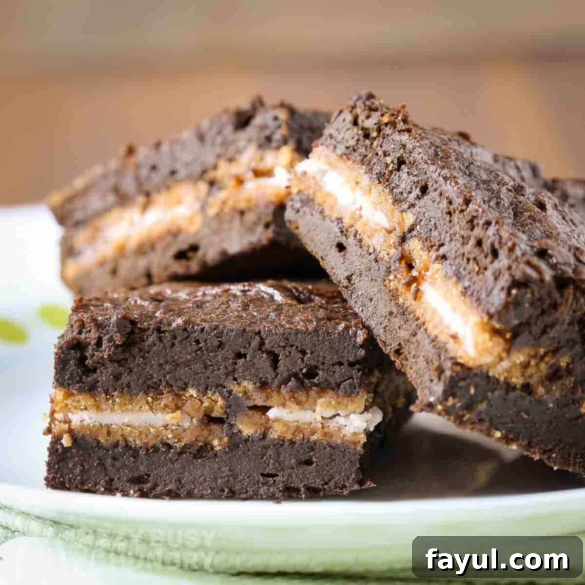 Side view of three pumpkin brownies with Oreo cookie layers clearly visible, resting on a white plate, highlighting their moist and fudgy interior.
