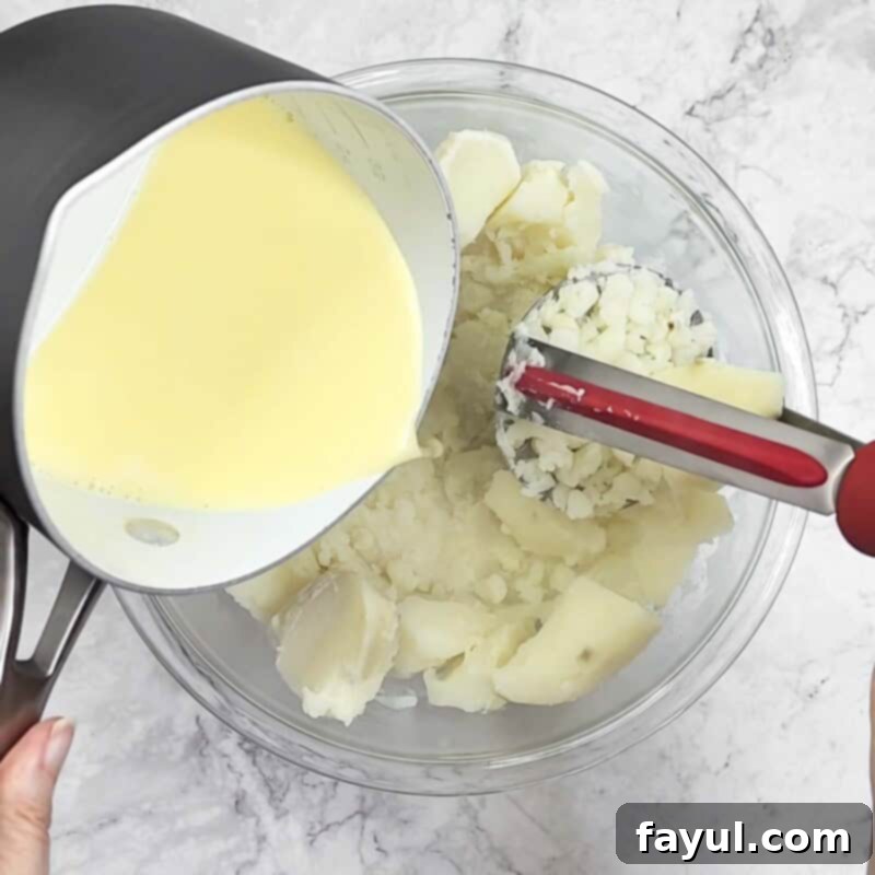 Overhead view of process shot 4 - add the butter mixture to the boiled potatoes and use a potato masher to combine.