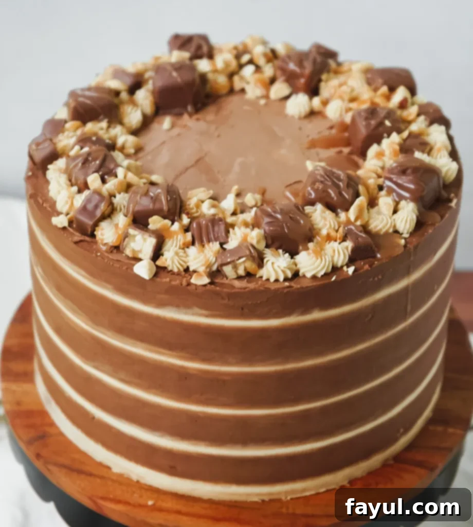 An assembled Snickers cake, showing multiple layers of chocolate cake and filling, ready for frosting.