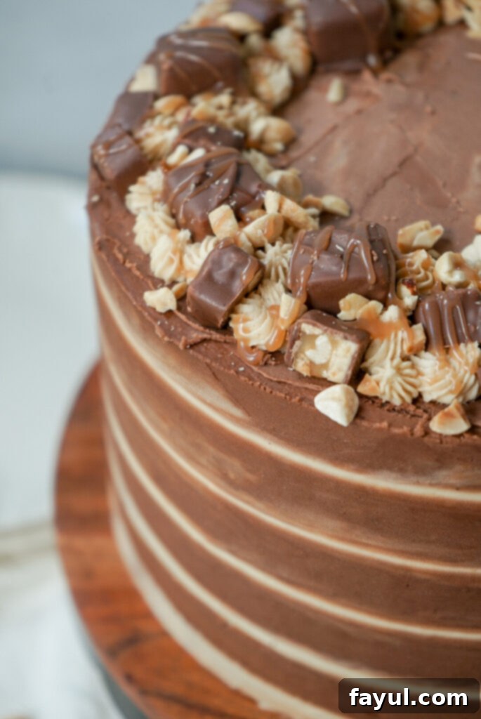 A beautifully decorated Snickers cake, ready to be served, showcasing the frosting and the layered structure.