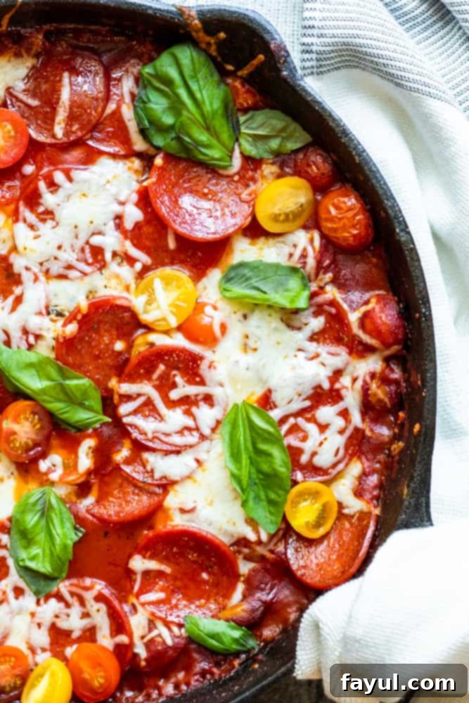 Overhead shot of chicken in a large black skillet, bubbling with sauce, cheese, and pepperoni.