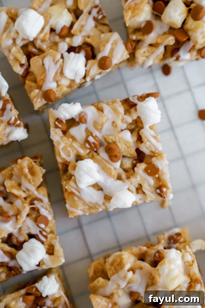 The Cinnamon Toast Crunch Cereal Bar mixture pressed into a parchment-lined baking pan, topped with extra marshmallows and cinnamon chips.