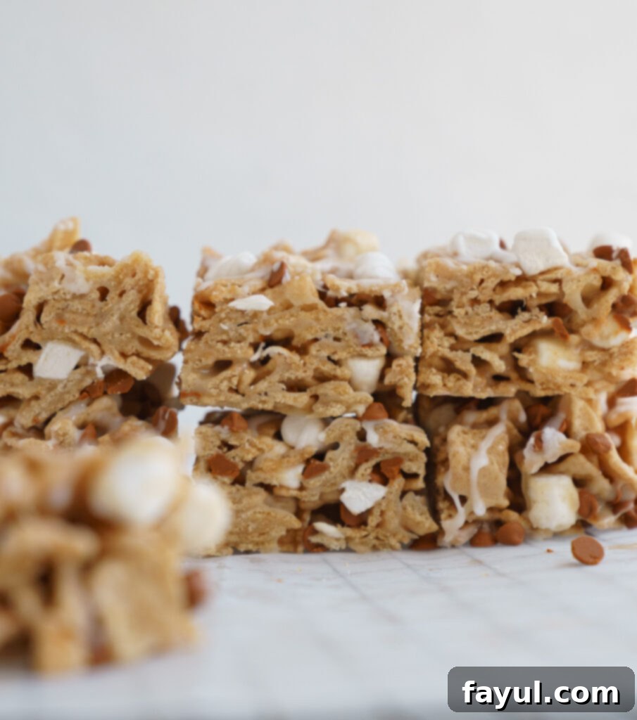 Two Cinnamon Toast Crunch Cereal Bars with glaze and cinnamon chips, one standing upright, on a wooden board, showcasing their texture.