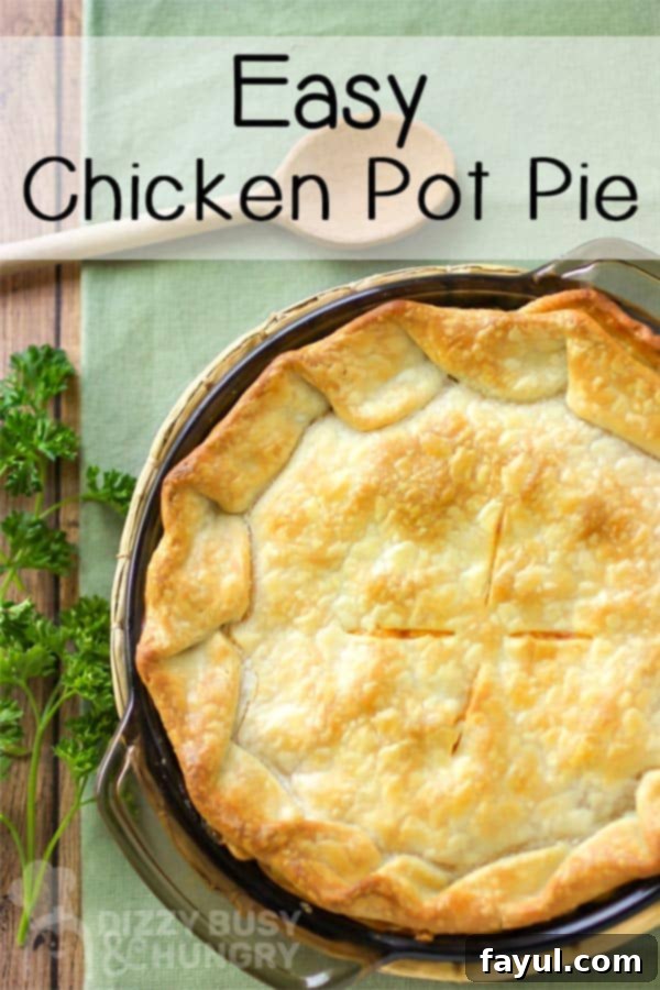 Overhead shot of full chicken pot pie in pan on a green cloth with a wooden spoon and herbs.