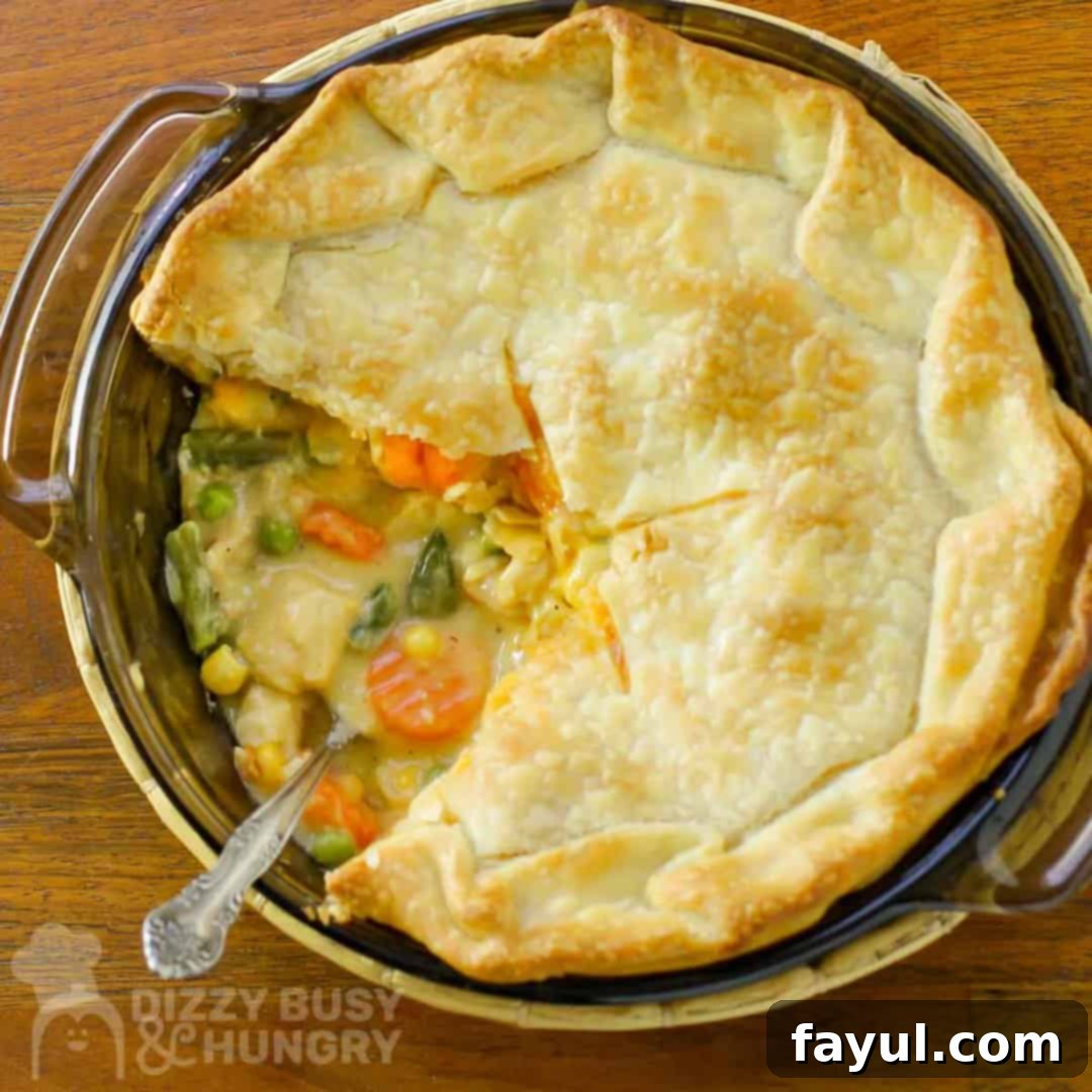 Overhead shot of chicken pot pie with slice taken out, left in the pan, with a fork.