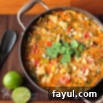 Close up view of a rich Brazilian fish stew garnished with fresh cilantro, with halved limes and a black spoon in the background.