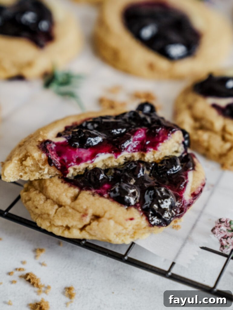 A batch of freshly baked blueberry cheesecake cookies on a wire rack.
