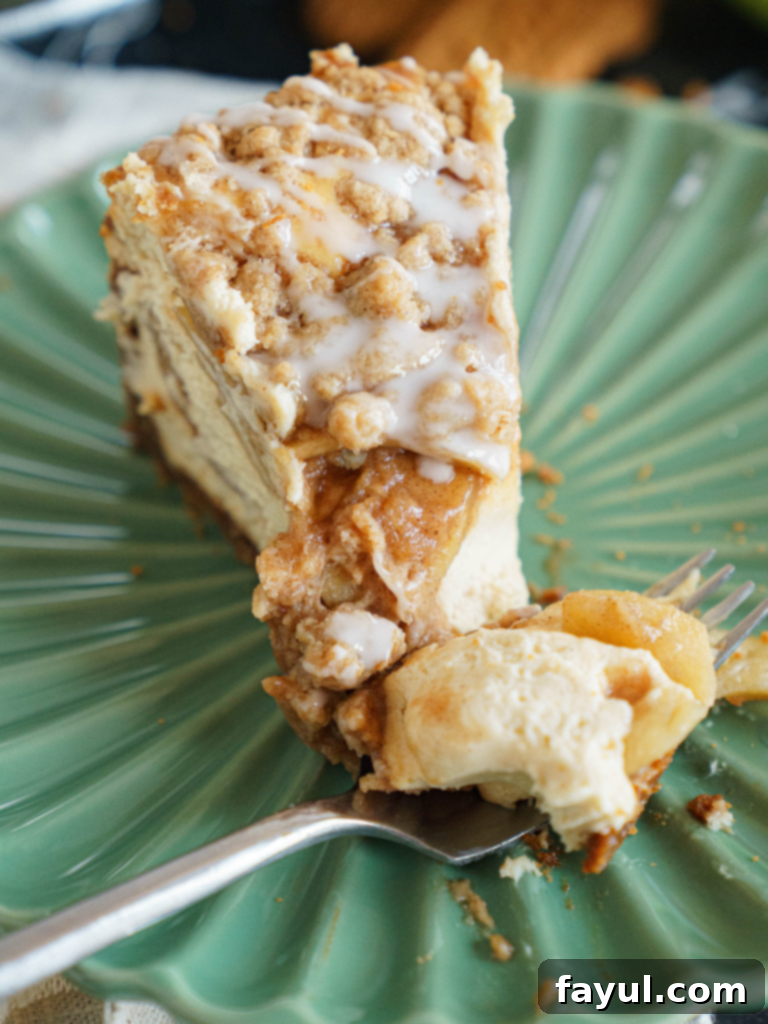 Homemade Apple Crisp Cheesecake with a golden streusel topping, creamy cheesecake filling, and a visible apple layer on a Biscoff crust, perfect for fall