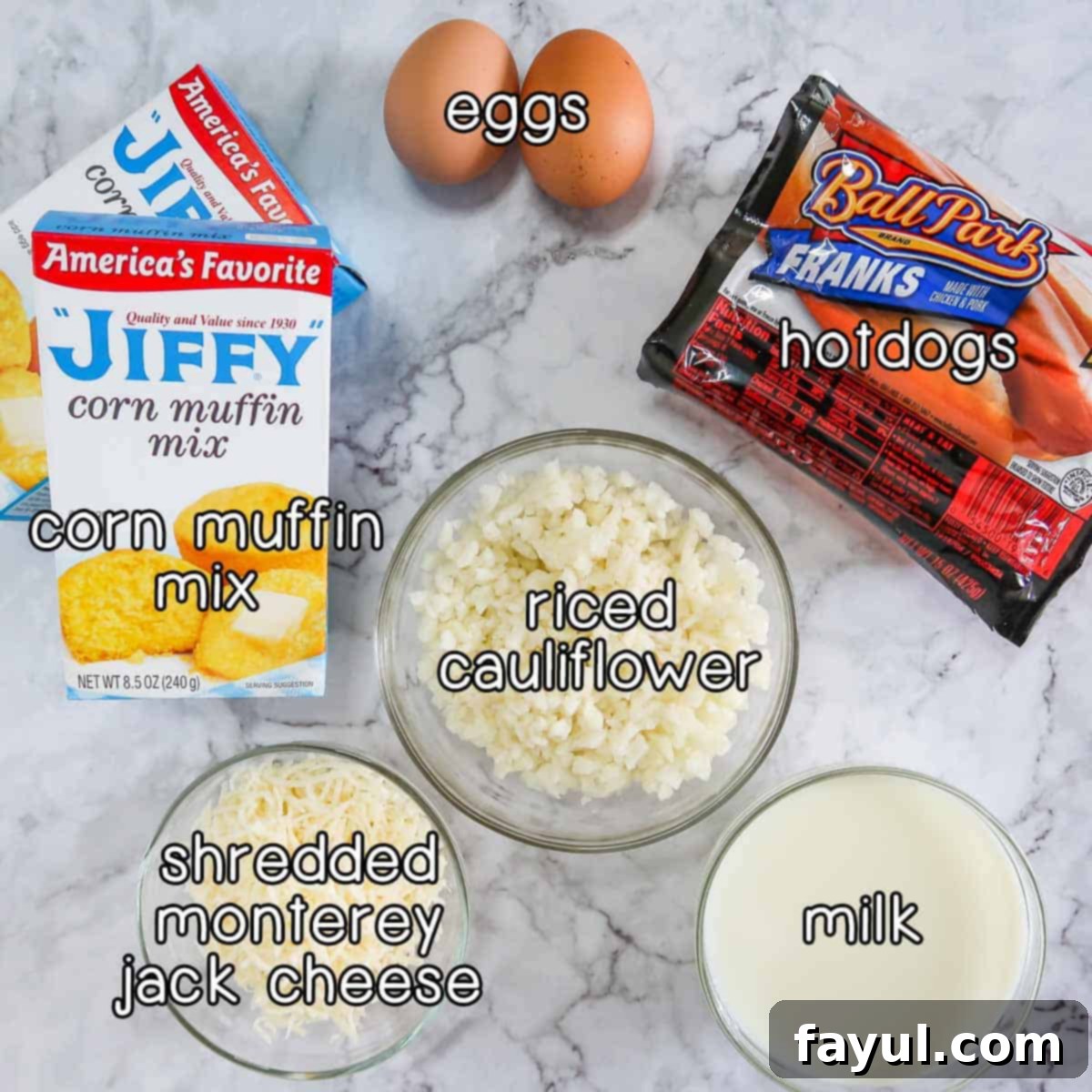 Overhead shot of ingredients - corn muffin mix, eggs, hotdogs, riced cauliflower, shredded Monterey Jack cheese, and milk.