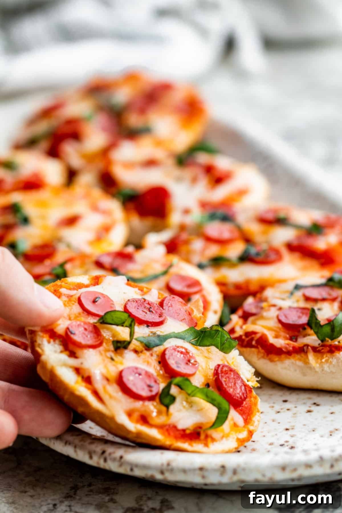 The Best Homemade Air Fryer Bagel Bites 6 Hand picking up pizza bagel.