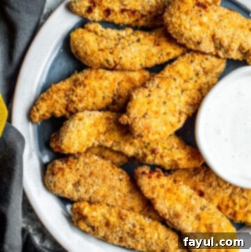Overhead shot of golden, crispy air fryer chicken tenders on a plate, ready to be enjoyed.