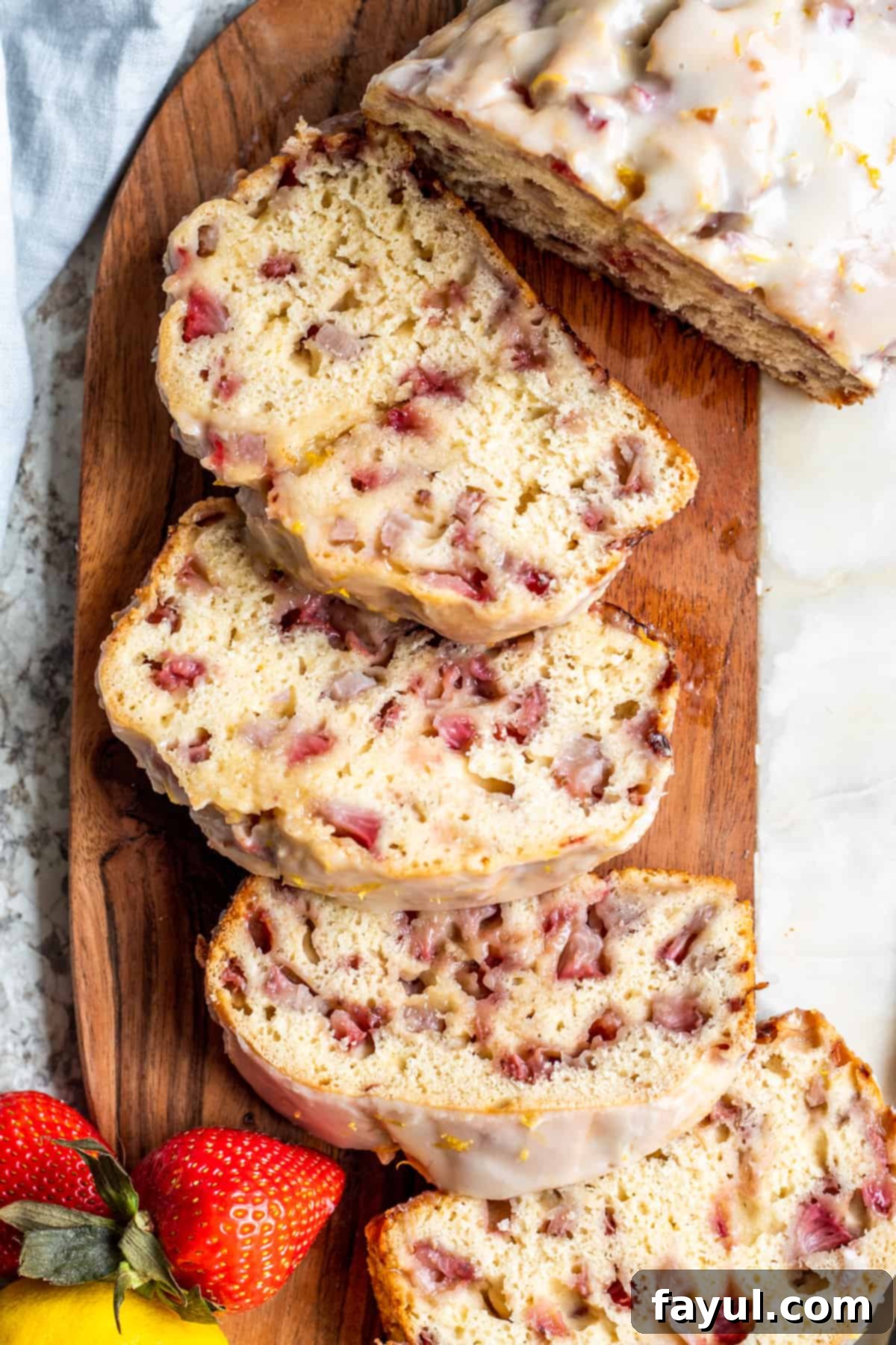 Sunshine Strawberry Lemon Loaf 2 Overhead shot of freshly baked strawberry loaf cake, beautifully sliced and arranged on a wooden cutting board, ready to be enjoyed.