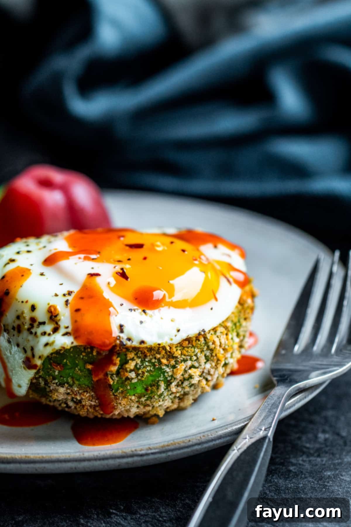 Speedy and Simple Air Fryer Avocados 7 Sunny side up egg on top of avocado on white plate.