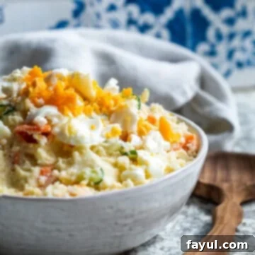Angle shot of Japanese potato salad in a white bowl with a wooden spoon, ready to serve.