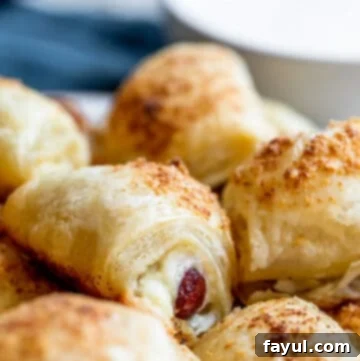 Straight on shot of golden brown cheesy pigs in a blanket arranged on a platter, ready to be served.