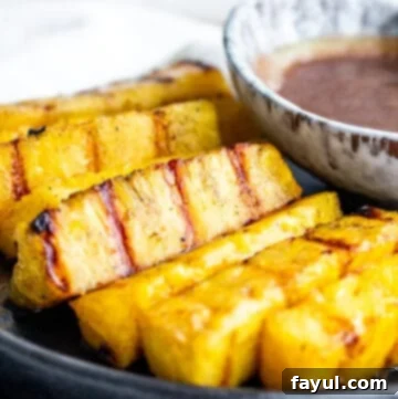 Cinnamon Kissed Grilled Pineapple 9 Strait on shot of pineapple on a plate with sauce.